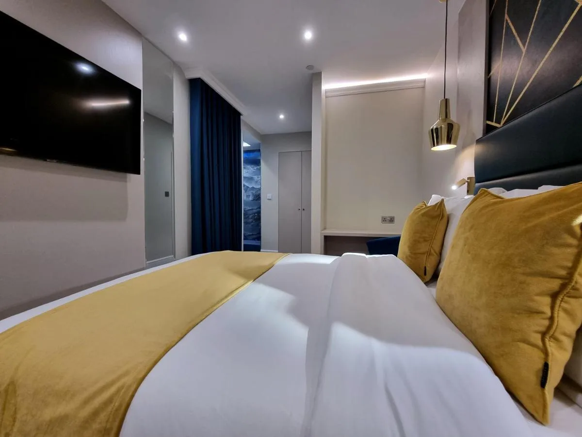 a bedroom with a large white bed with yellow pillows at NOX Kensington Gardens in London