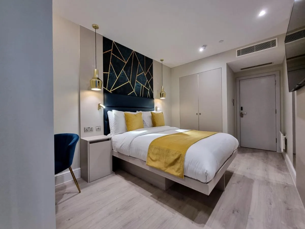a bedroom with a large bed with a yellow blanket at NOX Kensington Gardens in London